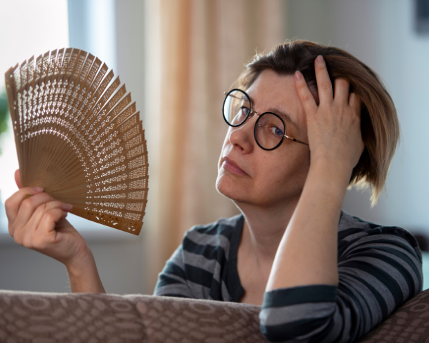 Woman fanning herself because her air conditioner is broken